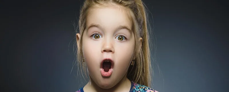 A young girl making a surprised face because she just found out what lice was!